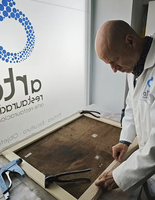 Técnico examinando o reparando el bastidor de madera de una pintura sobre lienzo para asegurar su estabilidad