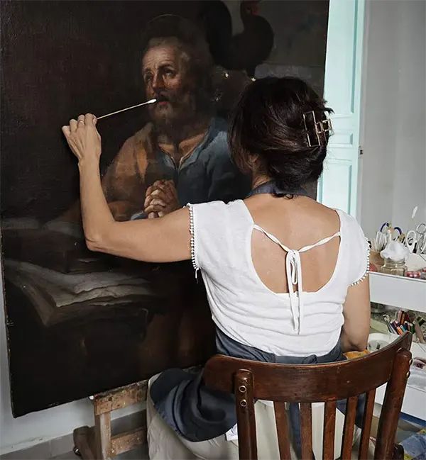 restauradora limpiando barniz en pintura al oleo